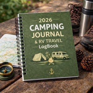May include: A green spiral-bound 2026 camping journal and RV travel logbook. The cover displays illustrations of a tent, campfire, RV, and anchor. A compass, map, hiking boots, and pine cones are also visible.