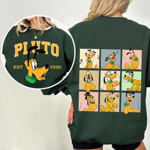 Könnte beinhalten: Dunkelgrünes Sweatshirt mit Pluto, dem Disney-Zeichentrickhund. Die Vorderseite hat ein kreisförmiges Design mit "PLUTO" und "EST 1930". Die Rückseite zeigt Pluto in verschiedenen Posen in farbigen Quadraten. Das Sweatshirt hat einen weißen Kragen.