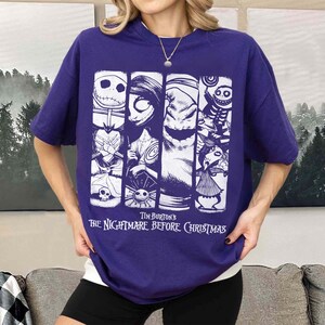 May include: A purple short-sleeve t-shirt featuring a white graphic print of characters from Tim Burton's The Nightmare Before Christmas. The design consists of four vertical panels displaying Jack Skellington, Sally, Oogie Boogie, and other figures.