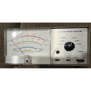 Puede incluir: Un analizador de motor de estado sólido vintage con una carcasa de metal plateado. El dispositivo presenta un dial con lecturas de RPM y Dwell, junto con controles para voltios, amperios y ohmios. El texto "SOLID STATE ENGINE ANALYZER" es visible.