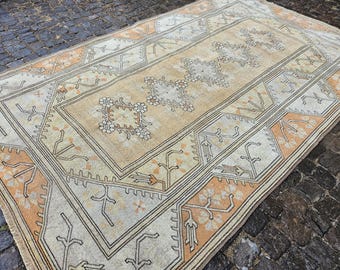 Könnte beinhalten: Ein rechteckiger Teppich im Vintage-Stil in Beige- und Pfirsichtönen. Der Teppich hat ein zentrales Blumendesign und einen detaillierten Rand mit geometrischen und floralen Mustern. Die Abmessungen des Teppichs sind nicht sichtbar.