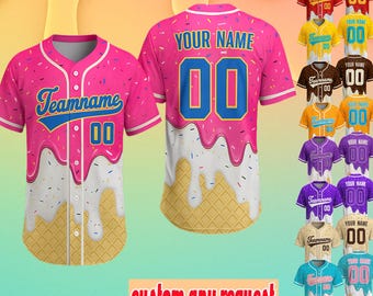 May include: Pink baseball jersey with a donut and waffle cone design. The jersey has the text "Teamname" and the number "00" on the front. The back of the jersey has the text "YOUR NAME" and the number "00". Additional jersey color options are displayed.