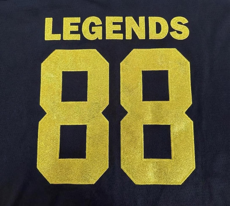 May include: A dark navy blue fabric background featuring the word LEGENDS printed in a bold, gold-colored font above the large number 88, which is also rendered in a matching gold-colored, textured, block-style typeface.