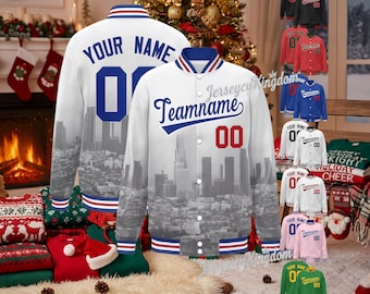 May include: White custom baseball jacket with a cityscape design, featuring the text "YOUR NAME" and "Teamname" with the number "00". The jacket has blue and red accents. Additional jackets in various colours are displayed.