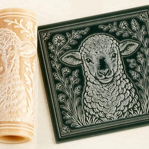 May include: A cylindrical beige patterned rolling pin and a square dark green tile. Both items feature an identical embossed design of a lamb surrounded by floral elements and foliage. The tile has a smooth, glossy finish with white details.
