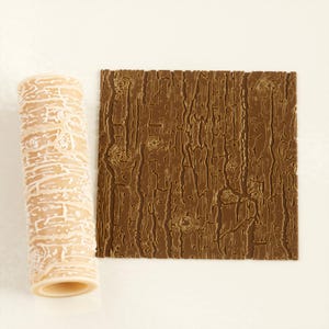 Peut inclure: Un rouleau à pâtisserie beige avec un motif de grain de bois blanc à côté d'une texture de grain de bois rectangulaire marron. Le rouleau est cylindrique, et la texture est carrée.