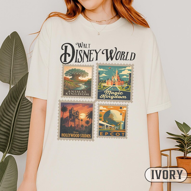 May include: Ivory-colored t-shirt featuring a vintage-style design with the text "Walt Disney World." The design includes four postage stamp-like images representing Animal Kingdom, Magic Kingdom, Hollywood Studios, and Epcot. The shirt is a relaxed fit.