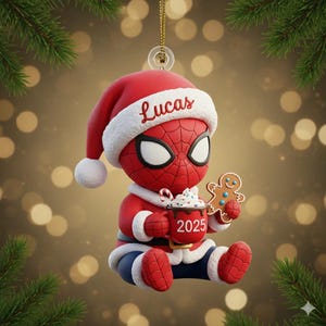 May include: A Christmas ornament featuring a red Spider-Man character wearing a Santa hat with the name "Lucas". The ornament holds a mug with "2025" and a gingerbread man. The ornament is red, white, and blue.