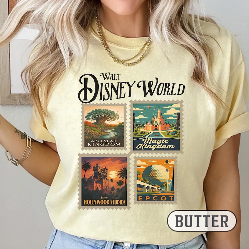 May include: Pale yellow t-shirt with a Walt Disney World design. The design features four postage stamp-style images representing Animal Kingdom, Magic Kingdom, Hollywood Studios, and Epcot. The shirt has a crew neck and short sleeves.