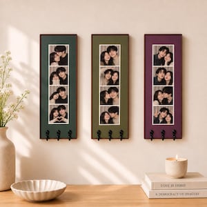May include: Three vertical rectangular wall-mounted organizers with dark wood frames. Each features a central strip of four stacked photo booth-style portraits of a couple and three black metal hooks at the bottom. The backings are dark green, olive, and purple.