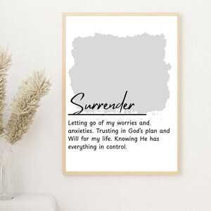 May include: A framed print with the word "Surrender" in elegant script. The print includes a gray watercolor-style shape and text that reads, "Letting go of my worries and anxieties. Trusting in God's plan and Will for my life. Knowing He has everything in control."