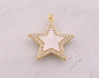 Può includere: Ciondolo a forma di stella color oro con un centro bianco e un bordo di piccoli cristalli trasparenti. Il ciondolo ha un anello nella parte superiore per il fissaggio a una catena. La stella ha cinque punte.
