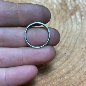 May include: A silver ring with a smooth, rounded surface.