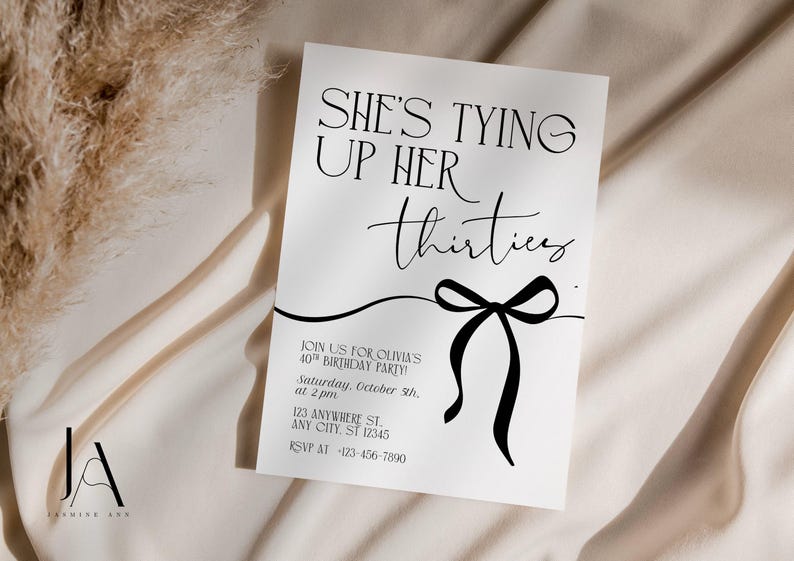 May include: A white invitation card with black text that reads "SHE'S TYING UP HER thirties". A black bow graphic is below the text. The invitation is for Olivia's 40th birthday party. The card is on a cream-colored fabric.