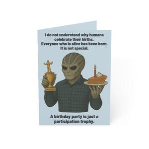 May include: A light blue greeting card features an illustration of an alien holding a trophy and a piece of cake. Text on the card reads: "I do not understand why humans celebrate their births. It is not special. A birthday party is just a participation trophy."