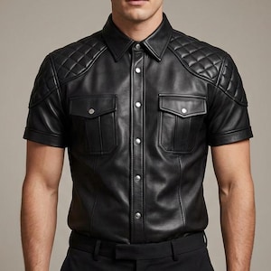 May include: A black leather short-sleeved shirt with quilted shoulder pads and two chest pockets. The shirt features a button-down front and a classic collar. The model is wearing black trousers.