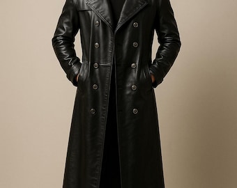 May include: A full-length black leather trench coat with a double-breasted design. The coat features a wide lapel collar and multiple buttons. The model is wearing black pants and boots. The coat is a classic outerwear piece.