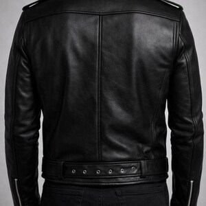 May include: Black leather jacket with a classic design. Features include a notched collar, shoulder epaulets, and a belt at the waist. The jacket has zippered pockets and cuffs. The model is wearing black jeans.