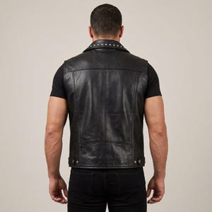 May include: Black leather vest with a studded collar and a classic design. The vest has a button closure and a tailored fit. A stylish and edgy piece of outerwear.