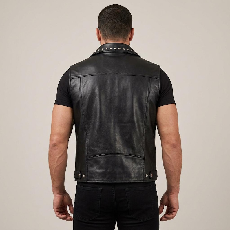 May include: Black leather vest with a studded collar and a classic design. The vest has a button closure and a tailored fit. A stylish and edgy piece of outerwear.
