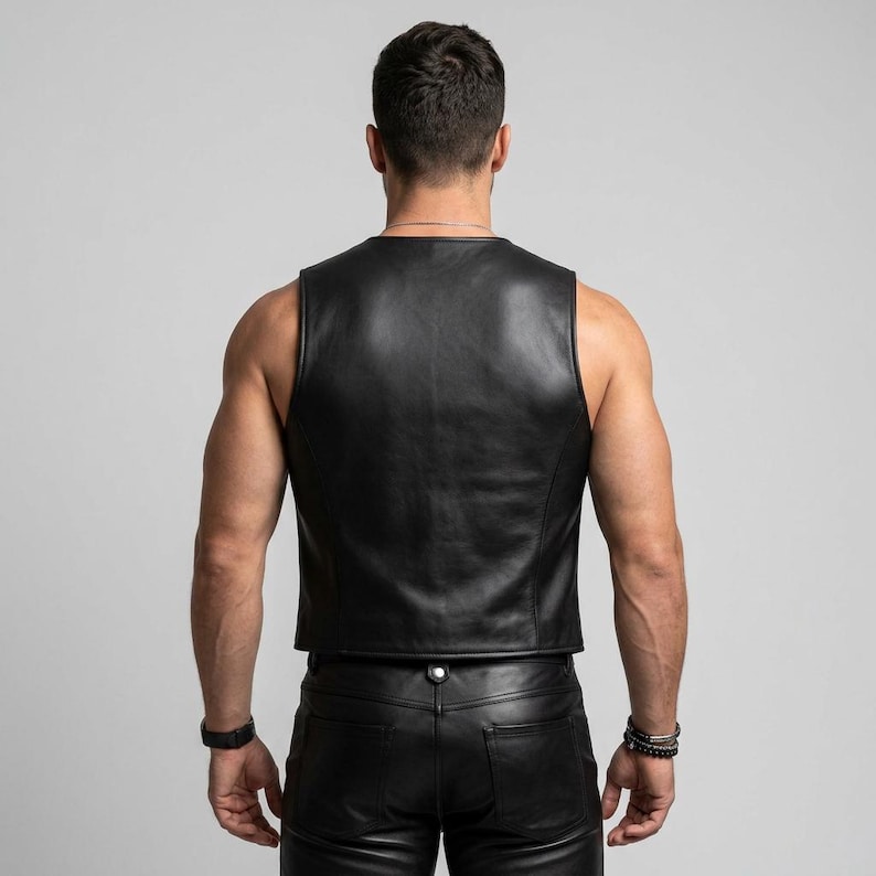 Op de afbeelding: Zwarte leren vest met een V-hals. Het mouwloze vest heeft een getailleerde pasvorm, die de gladde textuur en het klassieke ontwerp benadrukt. De afbeelding toont de achterkant van het vest. Het wordt gecombineerd met een zwarte leren broek.