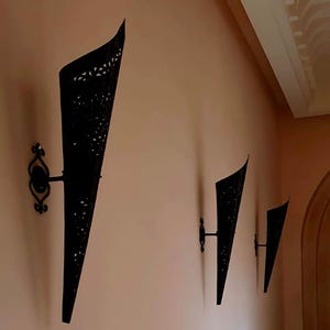 Die Kasbah-Fackel: Eine große, moderne marokkanische Wandleuchte, mattschwarzes, handdurchbrochenes Metall, auffällige Flurbeleuchtung