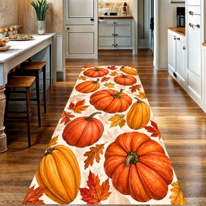 Peut inclure: Un tapis de couloir rectangulaire orné d'un motif répétitif de citrouilles orange et de feuilles d'automne multicolores dans des tons de rouge, jaune et marron sur un fond crème, conçu pour être posé sur un sol de cuisine en bois.