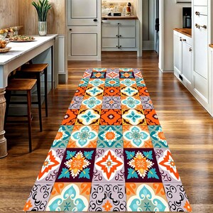 May include: A colorful runner rug with a geometric tile pattern. The rug features a repeating design of squares in shades of orange, teal, purple, and white. The rug is placed on a wooden floor in a hallway.