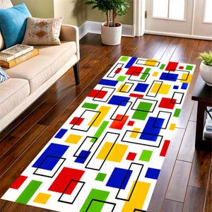 May include: A rectangular rug with a white background features a geometric pattern of red, blue, green, and yellow shapes outlined in black. The rug is placed on a hardwood floor.
