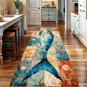 Puede incluir: Una alfombra pasillera rectangular larga con un gran gráfico de un pez azul orientado verticalmente. La alfombra presenta un diseño de patchwork con varios motivos florales en tonos azules, naranjas y crema sobre un suelo de cocina de madera.