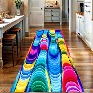 Könnte beinhalten: Ein farbenfroher Läuferteppich mit einem lebendigen, abstrakten Design. Der Teppich zeigt vertikale, geschichtete Muster in Blau-, Rosa-, Gelb- und Grüntönen. Der Teppich liegt auf einem Holzboden in einem Flur.