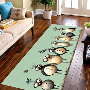 Peut inclure: Tapis rectangulaire avec un motif fantaisiste d'oiseaux de dessin animé aux grands yeux et aux détails de plumes variés. Les oiseaux sont disposés en rangée sur un fond vert clair. Le tapis est posé sur un parquet.