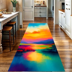 May include: A rectangular, colorful rug with a vibrant landscape design. The rug features a sunset scene with shades of orange, yellow, blue, and purple. The design includes a body of water and mountains.