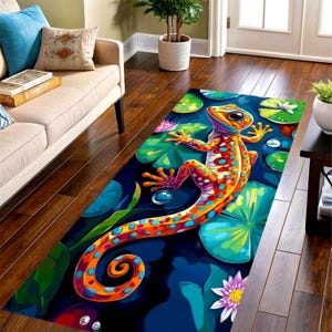 May include: A rectangular area rug featuring a vibrant, multi-colored gecko with orange, red, and yellow spots. The gecko is positioned over a dark blue background filled with bright green lily pads, water droplets, and pink water lily flowers.