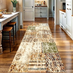 May include: A long rectangular runner rug featuring a patchwork design with various geometric, floral, and abstract patterns in shades of beige, brown, olive green, and muted blue, laid out on a polished wooden floor in a kitchen setting.