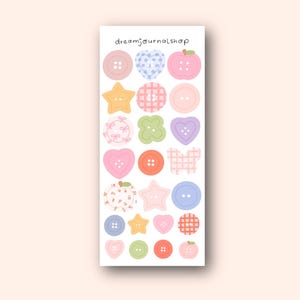 Könnte beinhalten: Ein Bogen mit Aufklebern mit verschiedenen Formen, darunter Knöpfe, Herzen, Sterne und Äpfel, in Pastellfarben. Die Aufkleber haben verschiedene Muster, wie Vichy-Karo und Blumendesigns. Der Text "dreamjournalshop" befindet sich oben.