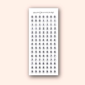 May include: A sheet of white number stickers with black text, ranging from 0 to 9. The stickers are arranged in a grid pattern, with the text "dreamjournalshop" at the top.