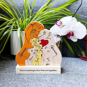 Puede incluir: Figura de madera de la familia El Rey León con las palabras "Grandpa" y "Grandma" en los lados. La figura presenta un corazón y los nombres de los niños. La base dice "There is nothing to fear if we are together."