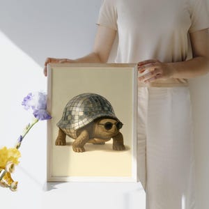 Könnte beinhalten: Gerahmter Kunstdruck mit einer skurrilen Illustration einer Schildkröte mit Sonnenbrille und einer Discokugel-Schale. Das Kunstwerk hat einen hellbeigen Hintergrund. Die Schildkröte ist braun und die Discokugel-Schale ist silber.