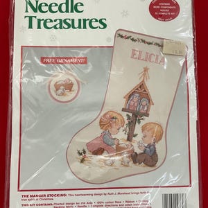 May include: A counted cross stitch kit for a Christmas stocking. The kit includes a charted design, floss, ribbon, and backing fabric. The stocking design features children and a nativity scene. The stocking measures 10" x 16".