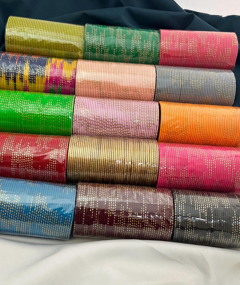 Op de afbeelding: Een verzameling kleurrijke armbanden in verschillende tinten, waaronder groen, roze, oranje en blauw. Elke armband is versierd met een delicaat stippenpatroon. De armbanden zijn netjes gerangschikt en tonen een verscheidenheid aan kleuren en ontwerpen.