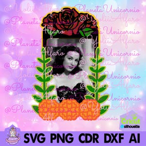 以下が含まれることがあります： 黒と白の女性の写真が、金色の額縁に入っています。額縁は赤いバラと緑の葉で飾られています。額縁の上にはオレンジ色のマリーゴールドの花が飾られています。女性は黒いドレスを着ています。