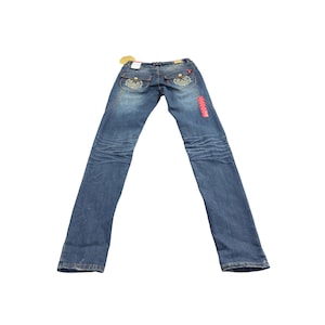 Könnte beinhalten: Blaue Jeans mit dekorativen Nähten auf den Gesäßtaschen und einem roten Etikett an der Seite. Die Jeans hat eine verwaschene Optik und einen geraden Beinverlauf. Ein kleines Etikett ist am Bund befestigt.