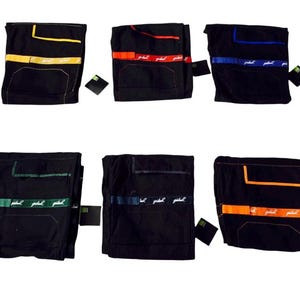 May include: Six pairs of black athletic shorts with coloured accents. Each pair features a different colour stripe across the front, including yellow, red, blue, green, navy, and orange. A small tag is attached to each pair.