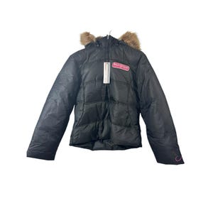 May include: Black puffer jacket with a faux fur-trimmed hood. The jacket features a quilted design and a pink logo patch on the chest. A tag hangs from the zipper. The jacket has a zipper closure and long sleeves.