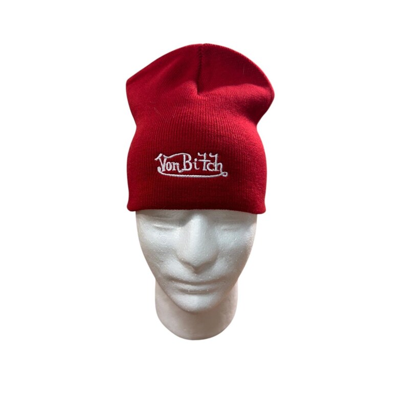 Puede incluir: Un gorro de punto rojo brillante con el texto VonBiTch bordado en hilo blanco en la parte delantera. El gorro tiene un dise&ntilde;o con dobladillo y se muestra sobre una cabeza de maniqu&iacute; blanca, resaltando el contraste entre la tela roja y el texto.