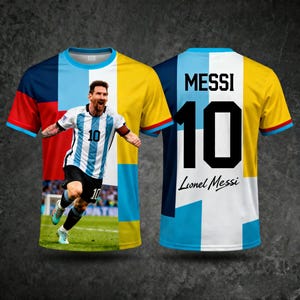 May include: A short-sleeved soccer jersey featuring a photo of Lionel Messi. The front of the jersey has a photo of Messi in a white and blue striped jersey with the number 10. The back of the jersey has the name "MESSI" and the number 10.