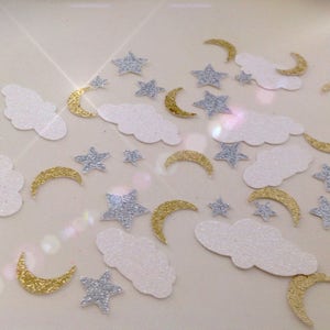 Könnte beinhalten: Eine Streuung von goldenen und silbernen Glitzerkonfetti mit Wolken, Sternen und Mondsicheln.