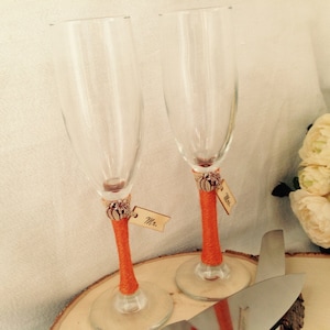 May include: Two champagne flutes with orange ribbon and pumpkin charms, with wooden tags that say "Mr." and "Mrs.".