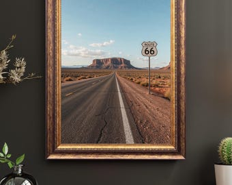 Könnte beinhalten: Gerahmter Druck einer Wüstenstraße mit einem Route 66-Schild. Die Straße erstreckt sich unter blauem Himmel in die Ferne, mit einer großen Tafelberg im Hintergrund. Der Rahmen ist aus dunklem Holz mit goldenen Akzenten.